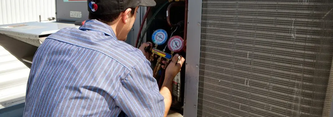 HVAC technician servicing a condenser unit in Williamson
